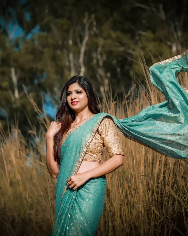 This dynamic shot from a photoshoot captures a soft, ethereal look. The makeup is natural and glowing, and the flowing saree adds a sense of movement and artistry.