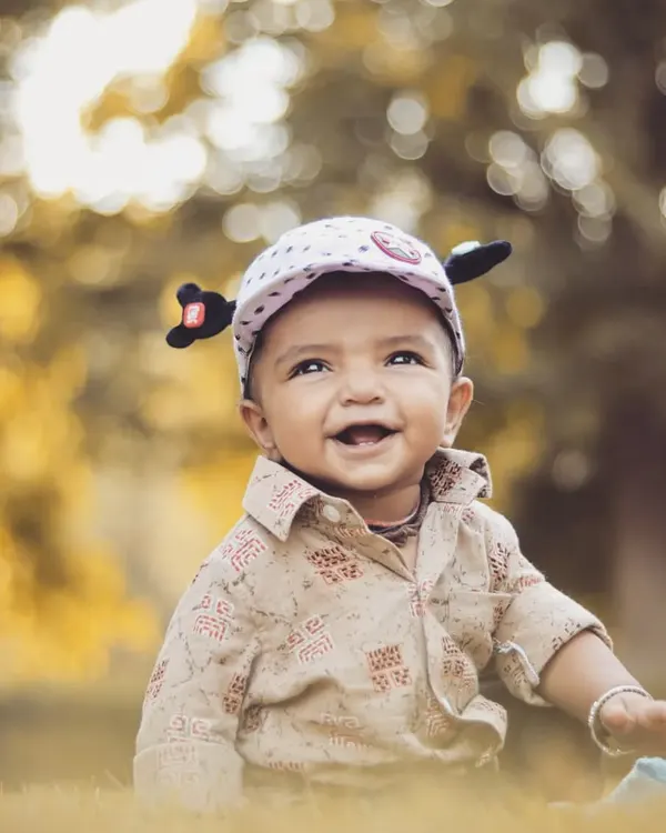 A beautiful outdoor portrait of a happy baby boy. The natural light and soft, leafy background create a warm and timeless feel, perfect for a child's portfolio.