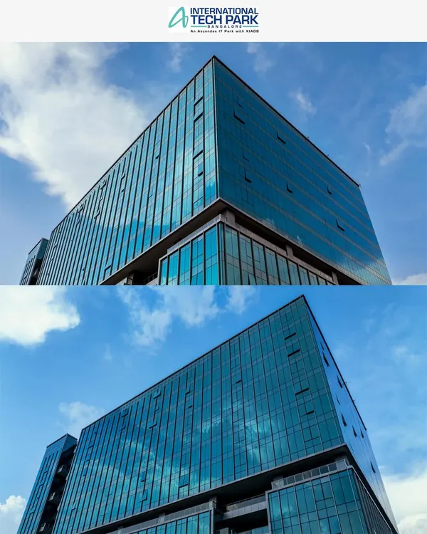 A low-angle aerial shot of the glass facade of a building at ITPL Tech Park, emphasizing its modern design against a clear blue sky. This is ideal for corporate branding and architectural portfolios.