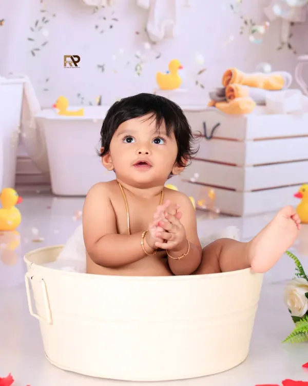 A classic splash session moment, with a baby looking up curiously from a mini bathtub. The bubbles and rubber ducks floating around add to the playful and fun atmosphere of the shoot.