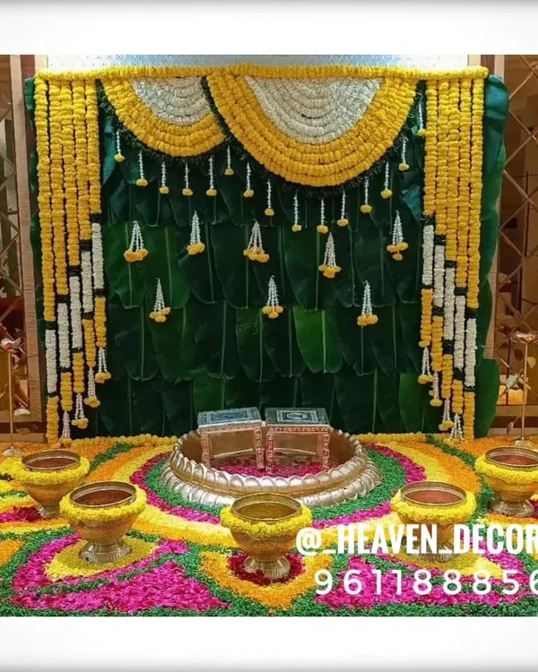 This is a complete setup for a homam or pooja ceremony. It features a traditional banana leaf backdrop, a vibrant floral rangoli on the floor, and brass urlis, creating a sacred and auspicious space.