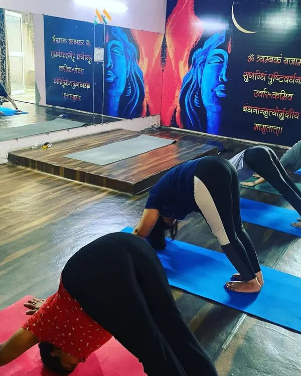 A typical teacher training session at our Noida studio. Here, students are in Adho Mukha Svanasana (Downward-Facing Dog), a foundational pose we break down in detail to understand its alignment and benefits. The large mirror helps students self-correct their posture.