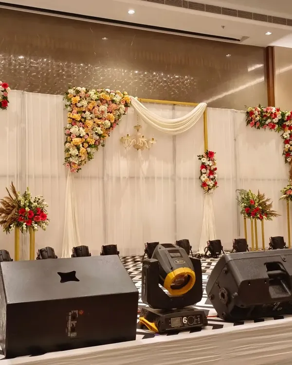 I designed this premium stage for a corporate function, combining elegant white fabric draping with asymmetrical floral arrangements. The setup included professional uplighting to create a sophisticated focal point for the event.