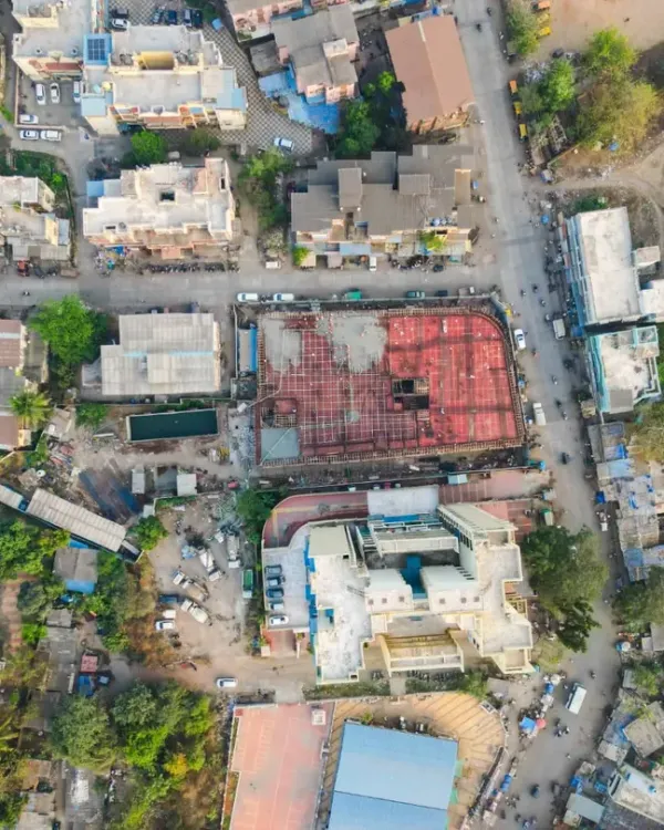 A wider aerial perspective of the construction site, showing its location within the surrounding neighborhood. This contextual drone shot is valuable for real estate marketing and urban planning documentation.