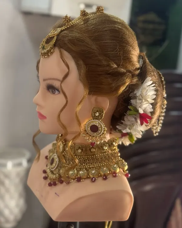A traditional bridal bun or 'khopa' created on a mannequin head. This style is adorned with flowers and jewelry, and mastering it is essential for any bridal artist.