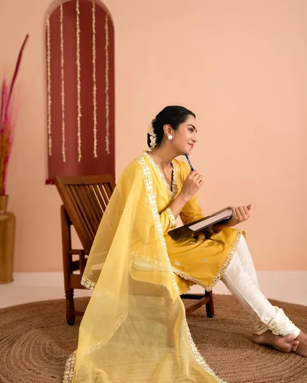 This studio portrait for an ethnic wear brand captures a thoughtful, elegant mood. The warm tones of the background complement the yellow kurta, while the pose highlights the flow of the dupatta.