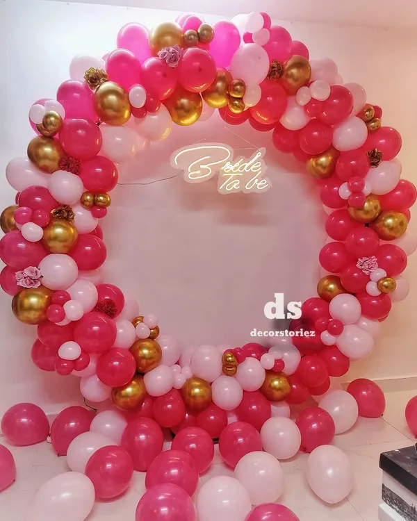 This full-ring balloon backdrop is one of our most requested items for bridal showers. We created this look with a vibrant mix of pink, white, and gold balloons, centered around a custom 'Bride to be' neon sign.