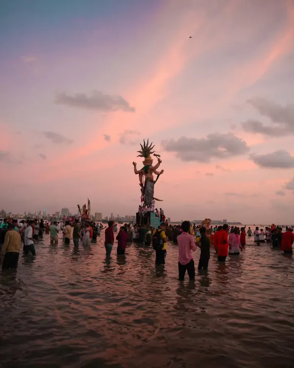 The Mumbaicha Raja idol during Visarjan, silhouetted against a breathtaking pink sunset. This photo captures the immense scale of the festival and the collective emotion of the farewell.