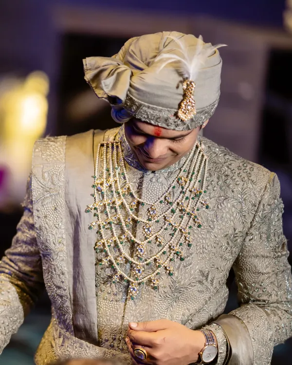 A close-up of the groom's wedding day look. We customized this Ankit V Kapoor sherwani to a sage green and paired it with a magnificent multi-layered pearl and emerald necklace to complete his royal ensemble.