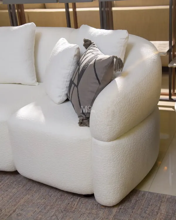 A close-up of the Aether Sofa's gracefully curved arm, showcasing the soft, looped texture of the high-quality bouclé fabric that invites you to sink in and unwind.