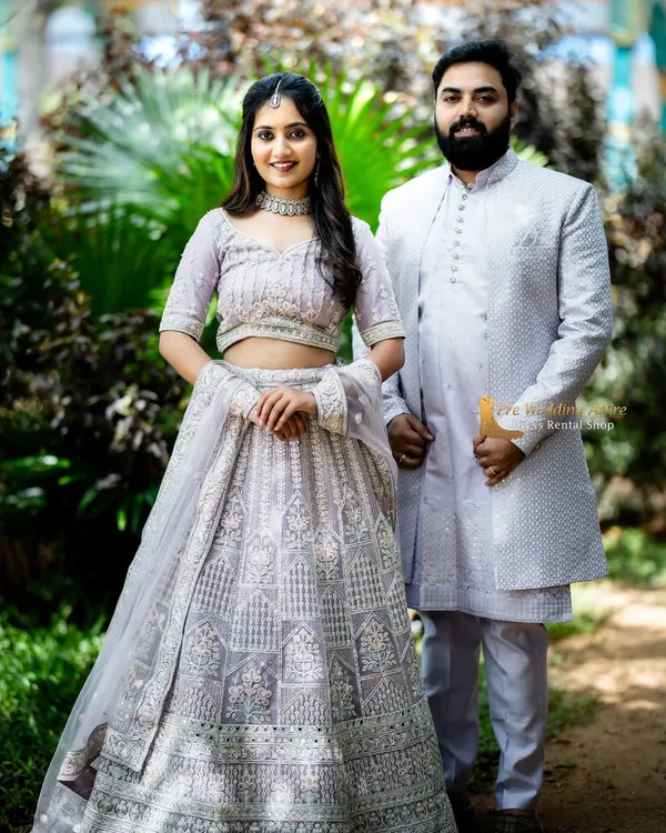 A full-length view of our coordinated lavender lehenga and sherwani set. The intricate silver embroidery is consistent across both outfits, creating a truly unified and elegant appearance for your couple photoshoot.