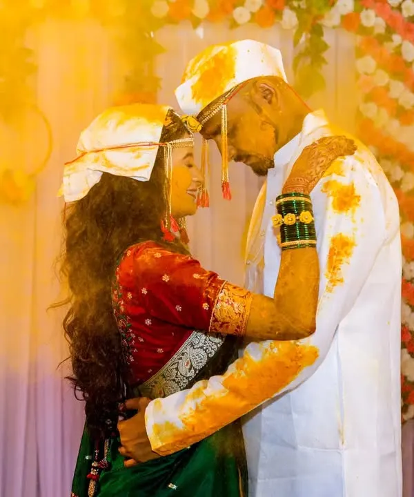 A beautiful, intimate moment during a Haldi ceremony. The golden glow of the turmeric and the couple's embrace create a warm and emotional photograph.