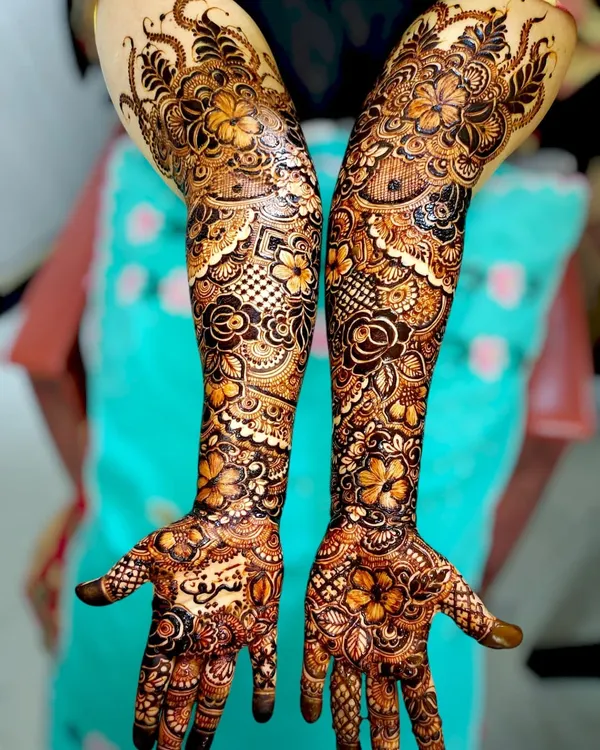 A complete bridal henna set, showcasing how the intricate patterns flow from the palm to the forearm. This design mixes floral elements with traditional Indian mehndi patterns.