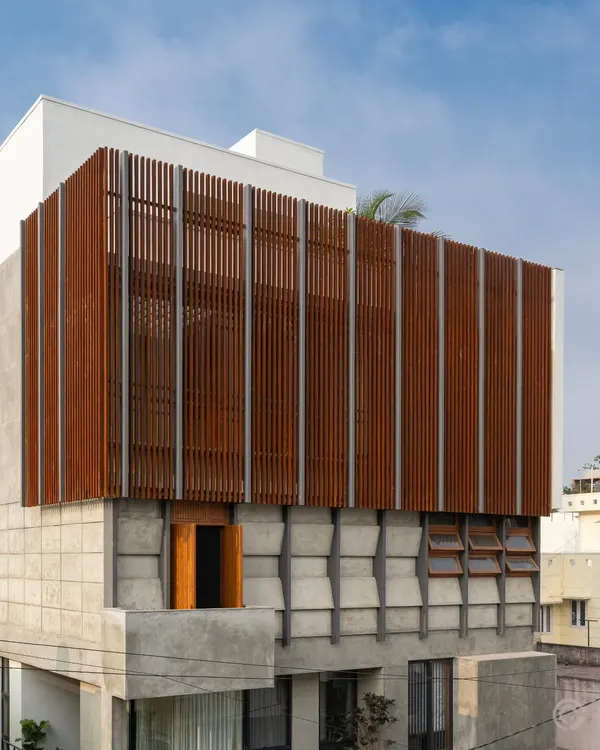 This is our 'Heirlooms in Concrete' residence in Bangalore. The facade demonstrates our approach to modern urban living, using a dynamic composition of raw concrete and a delicate wooden screen that provides both privacy and a connection to the outdoors.