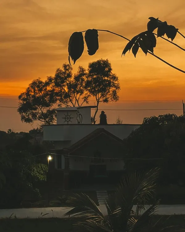 The silhouette of the ashram against a fiery sunset sky. Each evening here is a spectacle of color and a reminder of the beauty of the natural world.