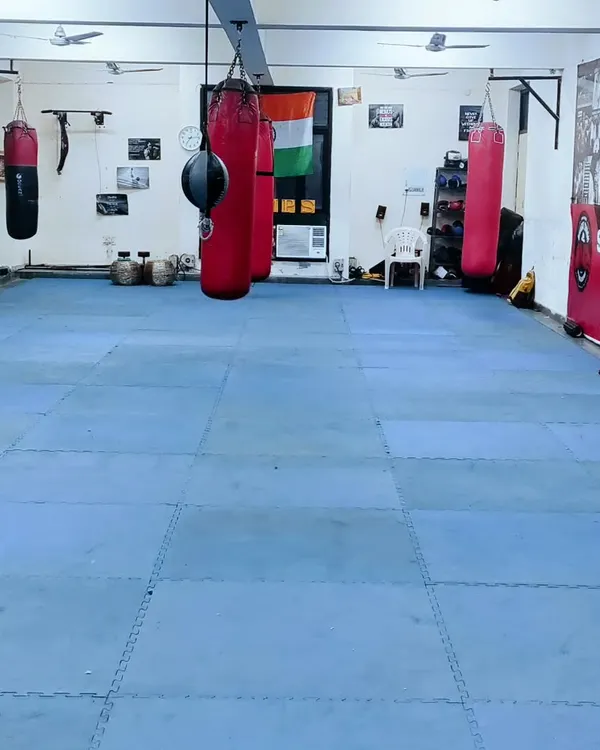 A full view of our training floor, equipped with multiple heavy bags and open mat space for drills and conditioning. This is our ground for hard work.