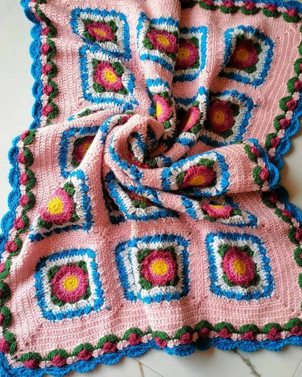 This is the Lydia blanket, a beautiful floral design made of many individual squares joined together. The swirling fabric shows the soft drape and generous size of the finished throw.