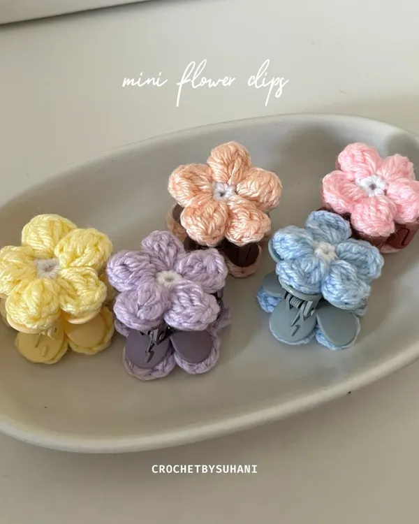 A close-up of my mini flower clips, displayed in a dish to show the variety of pastel colors available. Each clip features a small, detailed crochet flower on a secure clip base.