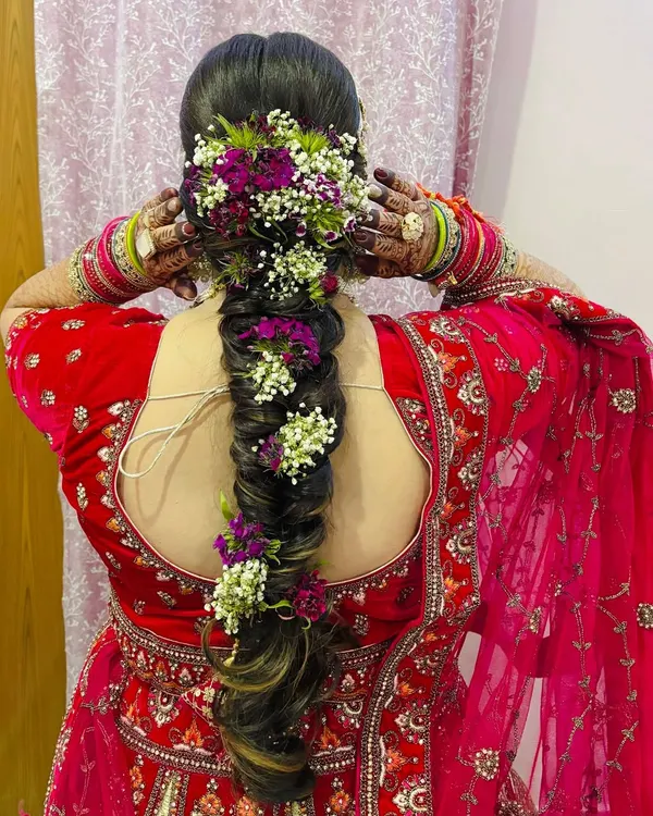A stunning view of a thick, floral bridal braid. I used a mix of purple and white flowers to match the bride's lehenga, creating a truly unique look.