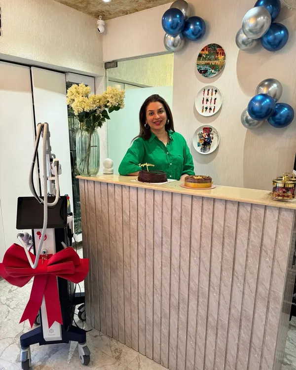 Standing at the reception desk of my clinic. We recently added a new machine to our practice, and I'm excited to offer the latest technology to help you level up your skincare game.