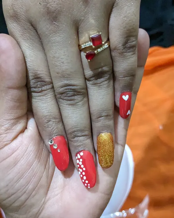 A bold and festive set of permanent nail extensions. This design combines classic red, sparkling gold glitter, delicate dot work, and even a few rhinestones for extra shine.