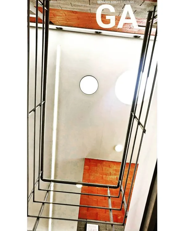 Looking up through a multi-story interior space towards a circular skylight. This design element, seen here in an industrial office, pulls natural light down through the building, illuminating the workspaces and reducing the need for artificial lighting.
