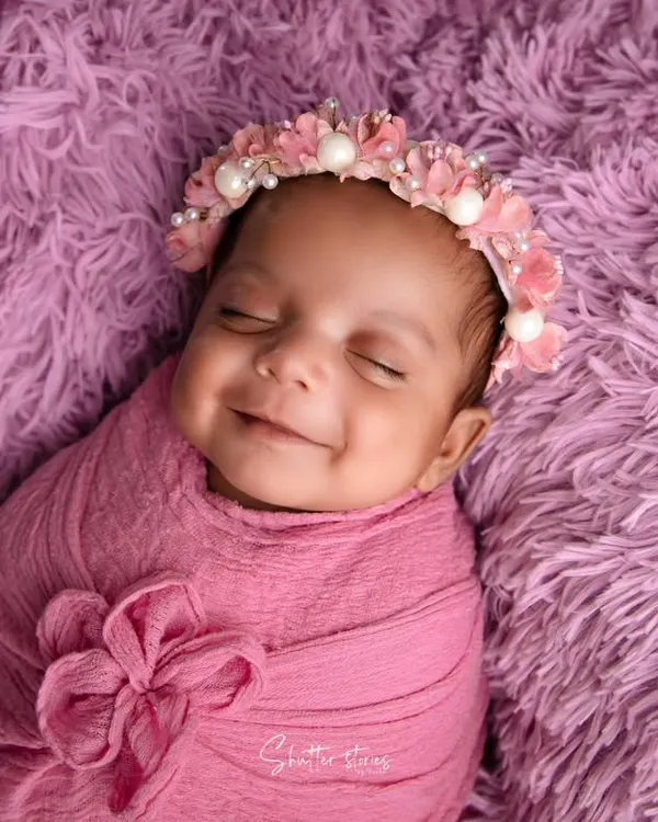 This is the kind of pure joy I aim to capture. This little one's sleepy smile, swaddled comfortably on a soft pink fur, is a perfect example of a peaceful and happy newborn session.