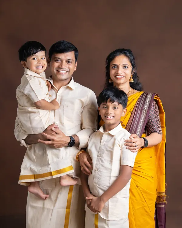 This is what family warmth looks like. I love capturing classic family portraits where everyone is dressed in beautiful, coordinated traditional Indian attire. The smiles here are so genuine, creating a timeless memory against a simple studio backdrop.