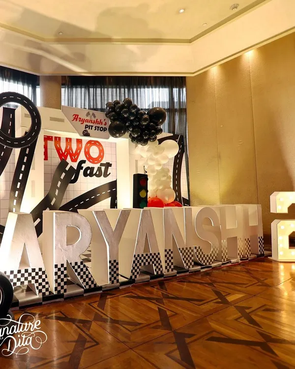 A 'Two Fast' second birthday party with a cool, monochrome Cars theme. I created a personalized pit stop with giant marquee letters, a road-themed backdrop, and a gas station prop.