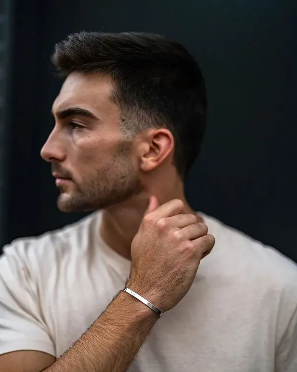 A man in a simple t-shirt wearing a silver cuff bracelet. The bracelet adds a touch of refined style to a classic, casual look.