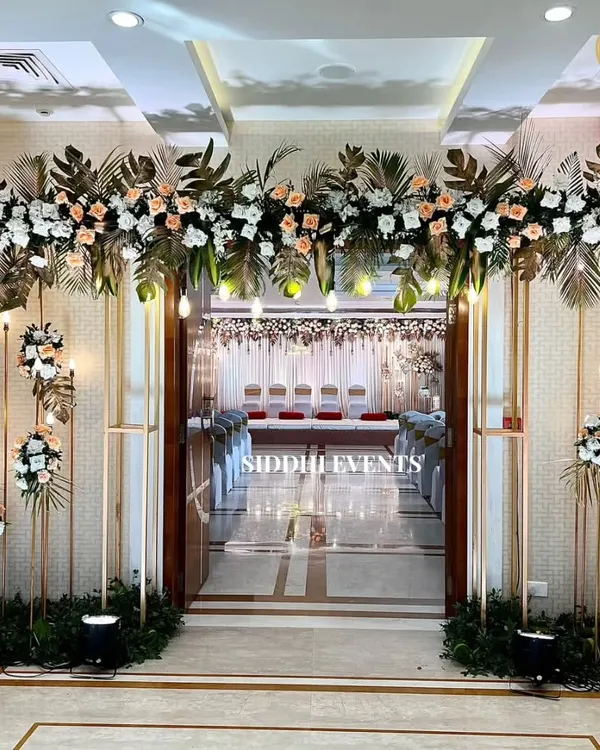 An exceptionally grand and elegant entranceway. We used tall golden frames, lush arrangements of peach and white florals, and soft lighting to create a breathtaking first impression.