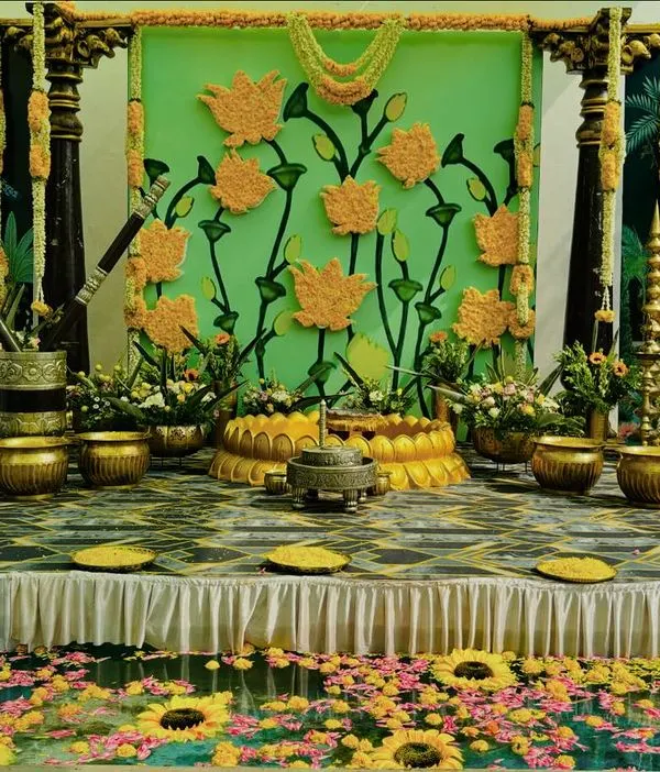 A spectacular Haldi stage setup featuring a custom backdrop of marigold flowers and traditional motifs. The poolside setting is decorated with floating flowers, creating a truly immersive experience.
