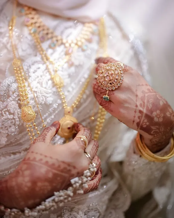 A close-up on the bride's hands, adorned with intricate henna and stunning gold jewelry. These details are a beautiful part of the bridal story.