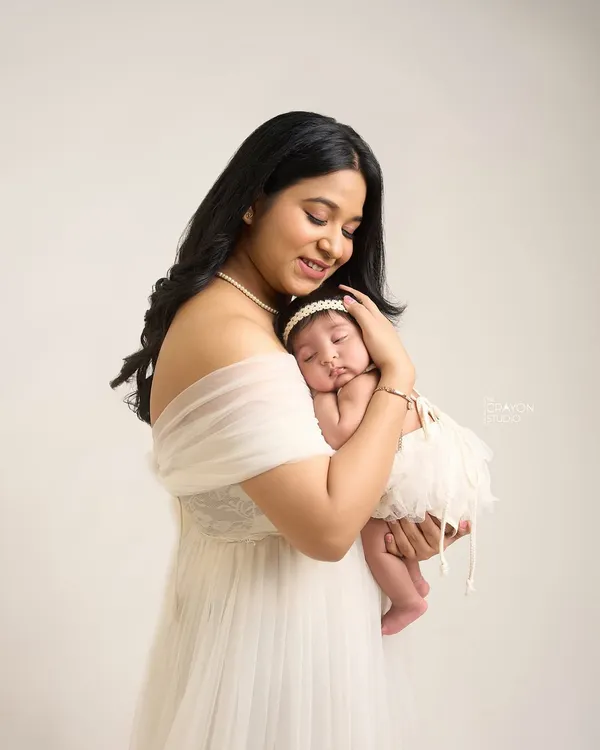 A mother's gentle embrace, holding her newborn daughter close. This portrait captures the overwhelming love and tenderness of the first few days of motherhood in a simple, elegant studio setting.