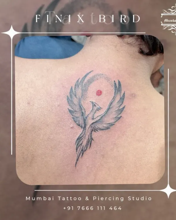 A phoenix rising, tattooed on the back. This symbol of rebirth and new beginnings is rendered with soft grey shading to give the wings a sense of light and movement.