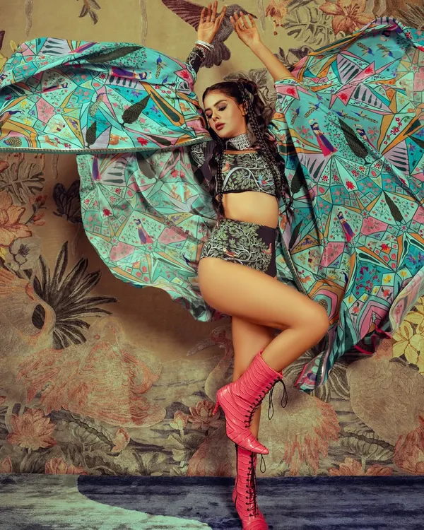A high-energy shot from an editorial with Priyanka Chahar Choudhary. The makeup is bold and defined to match the vibrant styling and dynamic pose.