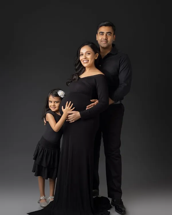 A beautiful portrait of a growing family. The older sister-to-be gives her new sibling a hug, a perfect moment of connection.