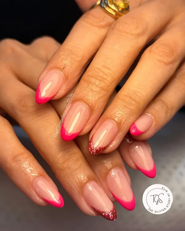 A vibrant and modern take on the French manicure. This set features sharp, almond-shaped nails with bright pink tips and a sparkling red glitter accent nail.