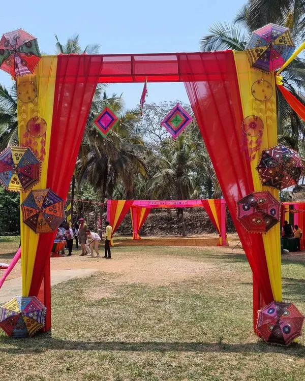 Another view of the festive entrance for the GIVA Holi corporate event, showcasing the vibrant yellow and red drapes and decorative umbrellas.
