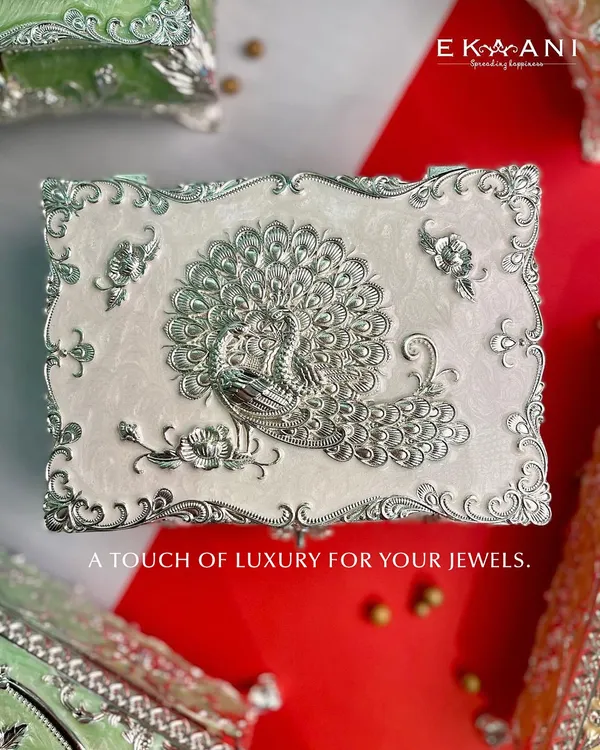 A touch of luxury for your jewels. This white enamel box features a stunning silver peacock, its feathers unfurled in a display of regal beauty. It is a perfect piece for your dressing table.