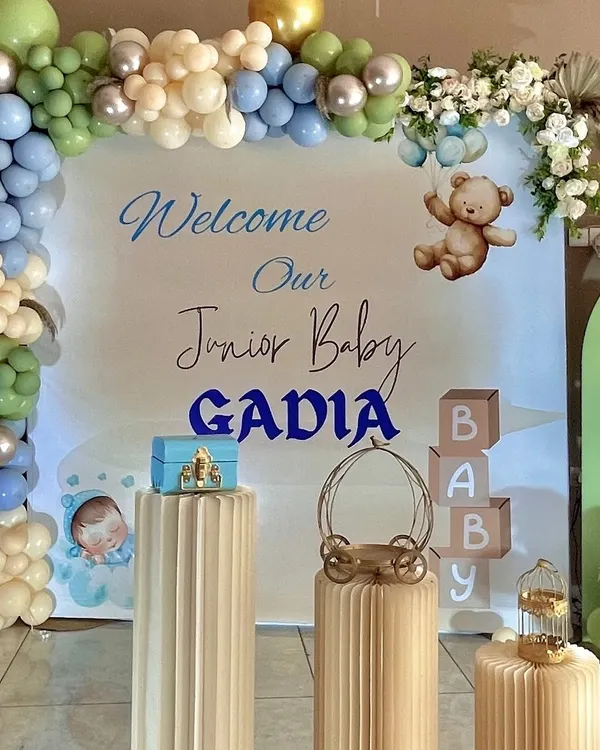 A 'Welcome Baby Boy' setup for the Gadia family. This design features a personalized backdrop, a gentle color palette of sage green, blue, and beige balloons, and cute teddy bear accents.