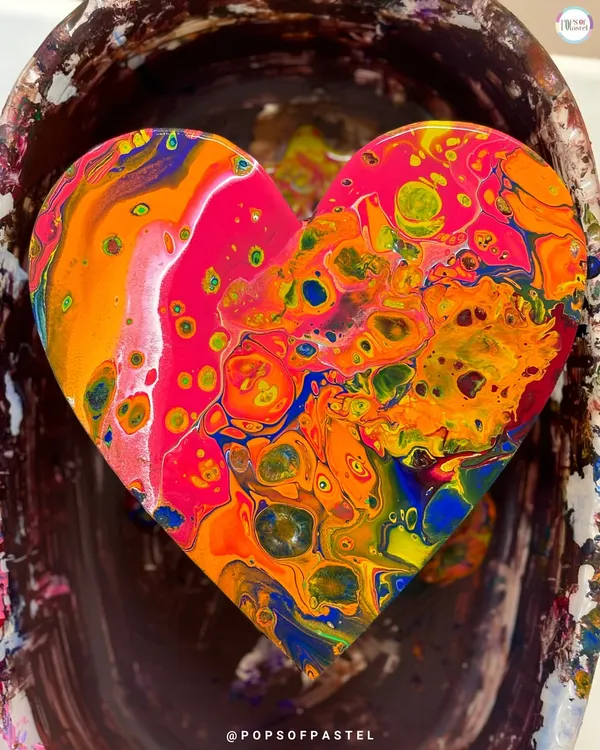 A close-up of a finished fluid art heart, bursting with vibrant orange, pink, and blue cells. Using silicone oil helps create these incredible, organic patterns, and we'll show you how.