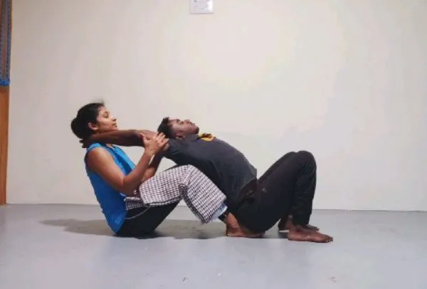 Here, I am assisting a student in a gentle backbend, using my body to provide stable support. This allows her to open her chest and thoracic spine with a sense of security and trust.