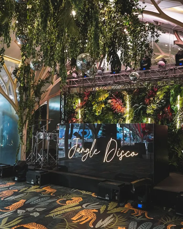 The centerpiece of our "Jungle Disco" theme. We designed a custom DJ booth framed by lush foliage and neon lights, creating an energetic focal point for the evening's celebrations.