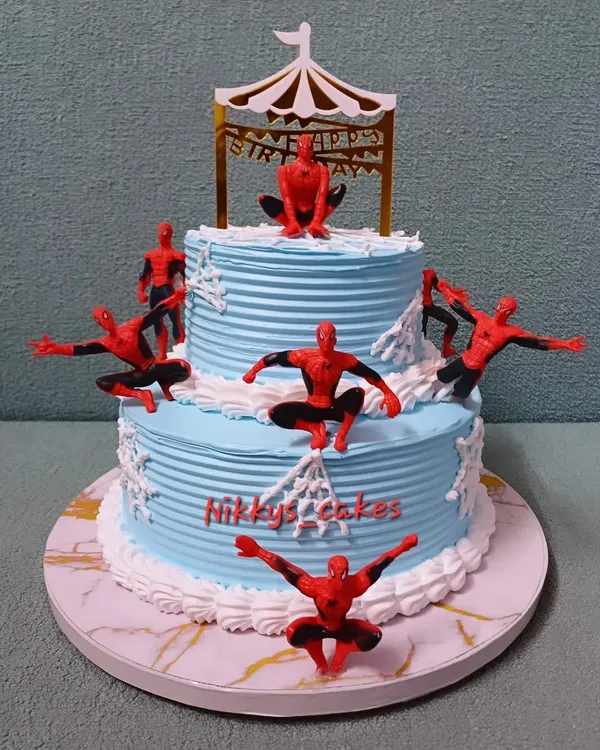 This two-tier Spider-Man cake is perfect for a young superhero fan. It features multiple Spider-Man figurines in action poses, climbing up the blue web-textured tiers, ready for a birthday adventure.