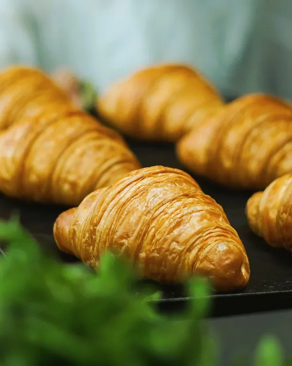 A close-up of our perfectly baked, flaky croissants. These are a Sunday morning essential, best enjoyed warm with butter and jam or our hazel coco spread.