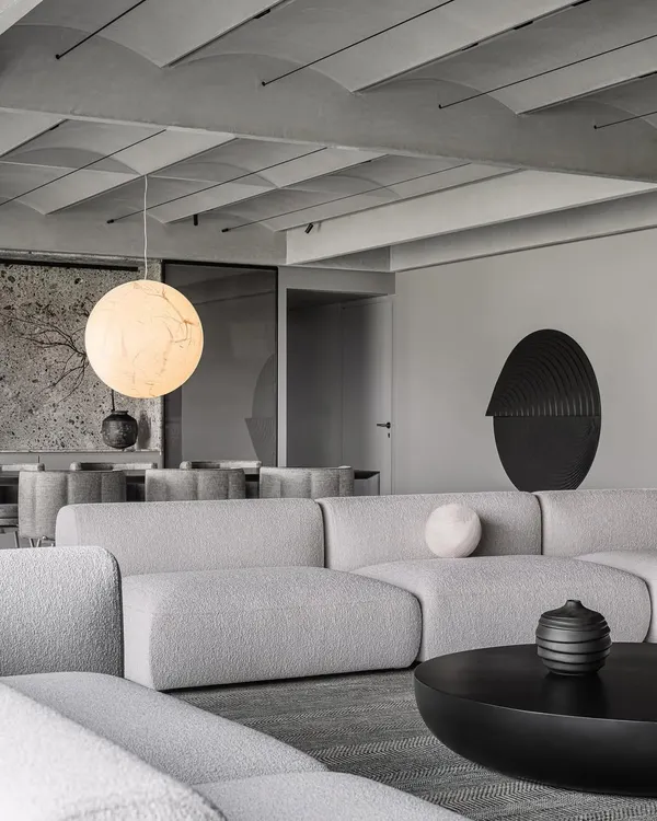 A view of the formal living area, showing how the modular sofa and dark coffee tables anchor the space beneath the geometric vaulted ceiling.