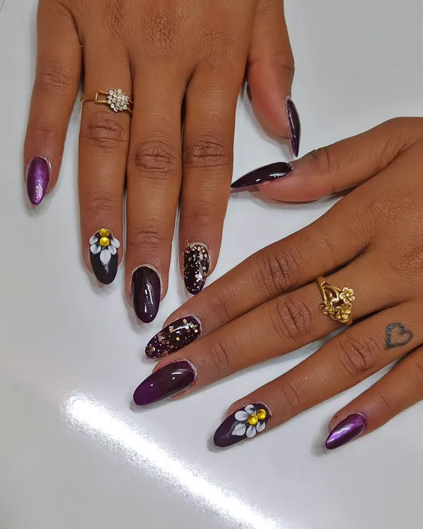 A closer look at the 3D floral nail art. Each petal is sculpted by hand, creating a raised texture that you can see and feel. This is paired with a deep purple polish and a shattered glitter accent nail.