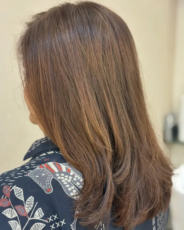 A classic layered haircut that adds movement and removes weight from medium-length hair, styled to show off the fresh, clean lines.
