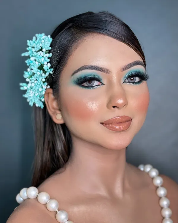 A full-face view of the blue smokey glittery eye makeup. This look is perfect for a cocktail party or reception, pairing the dramatic eye with a glossy nude lip and contoured cheeks to create a balanced, high-fashion look.